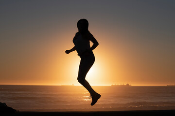 Fototapeta na wymiar silhouette of woman jumping on the beach at sunset