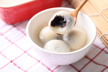 Tangyuan, Chinese dessert made of ball glutinous rice flour and filled with black sesame in ginger...