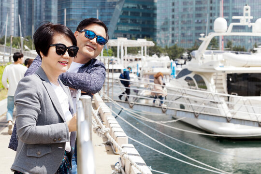 Middle Aged Couple Staring At The Camera In Front Of A Yacht
