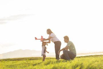 Asian children playing cardboard airplane together in the park outdoors