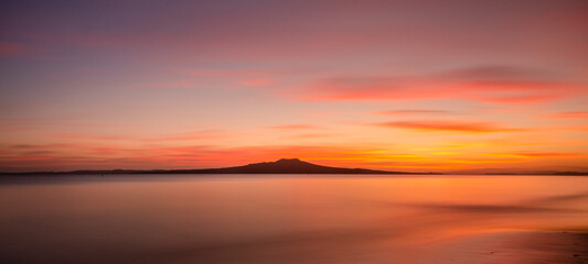Fototapeta na wymiar Milford Beach at dawn with Rangitoto Island in the distance, Auckland.