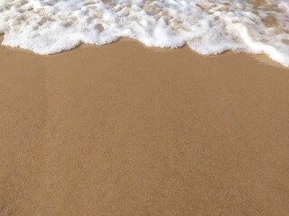 Fototapeta na wymiar Soft waves of the ocean on a sandy beach with blue calm waves. Chilaw, Sri Lanka