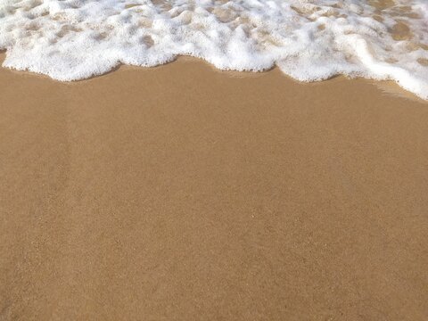 Soft waves of the ocean on a sandy beach with blue calm waves.  Chilaw, Sri Lanka