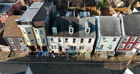 Trash on sidewalk by urban American homes. Poverty in inner city America. Aerial truck shot.