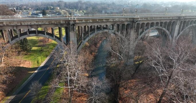 Side profile of concrete bridge arch. Aerial flight over road and stream river in Allentown Pennsylvania USA.