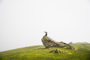 Man seating on the top of mountain at Foggy weather, hiking and climbing, Khaliya top, Munsiyari, Uttarakhand, India.