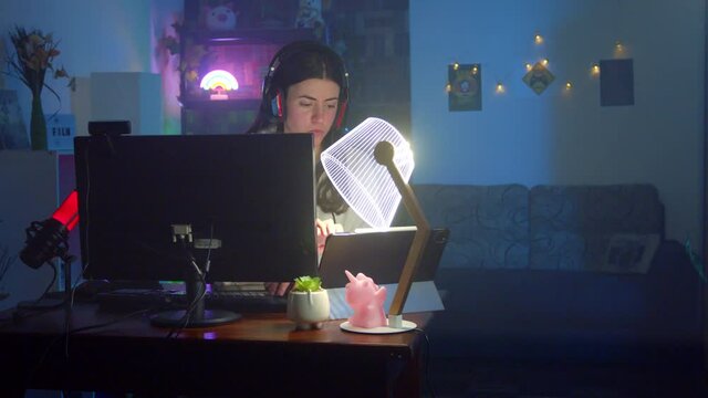 Young gamer woman using an iPad on pc desk at home