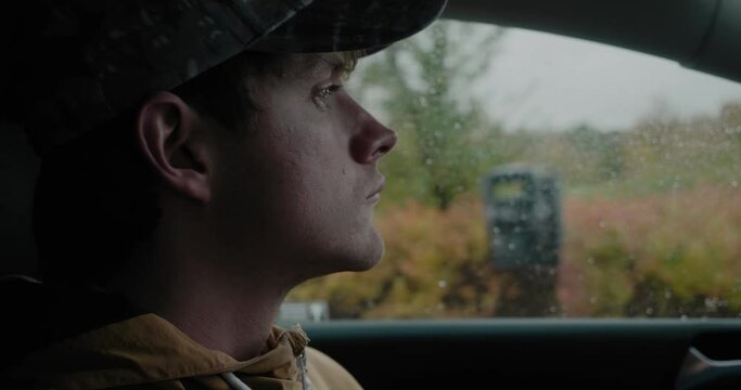 Young White Man Parking His Car In The Rain While Talking and Chewing Gum - Handheld Close Up