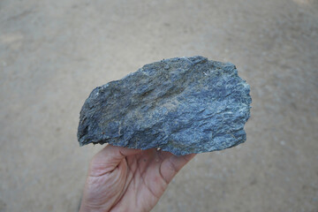 Raw of serpentine mineral rock in the hand of a geologist.