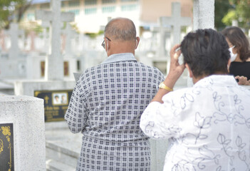 Back view of asian senior couple standing for mourn in front of the grave to remember the deceased...