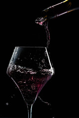 Fototapeta na wymiar Red drink is poured into a glass. Black background.