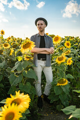 Portrait of a handsome country man in a hat in a sunflower field