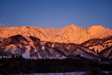 Morning view of Hakuba Miyama river and red mountain. Snow around three mountains of Hakuba Nagano prefecture, Japan.