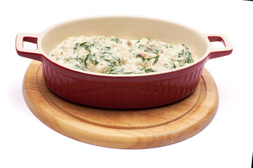 Delicious meatballs with spinach in a creamy sauce in baking dish on white background