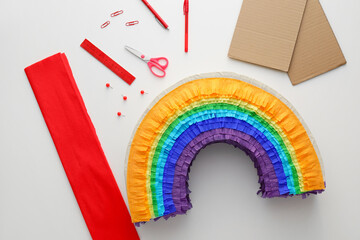 Materials for making Mexican pinata in shape of rainbow on white background