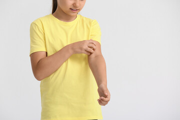 Little girl scratching herself on light background
