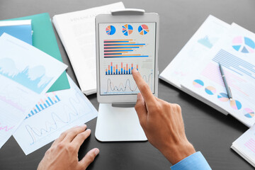 Businessman working with tablet computer at desk in office, closeup