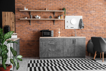 Interior of modern kitchen with counters and hanging pegboard on brick wall