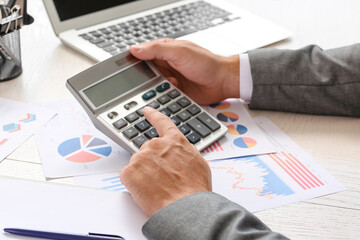 Fototapeta na wymiar Young businessman working with calculator at table in office, closeup