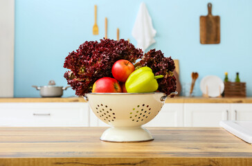 Colander with fresh food on wooden table top in kitchen