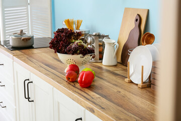 Fresh food and kitchen supplies on wooden table top near blue wall