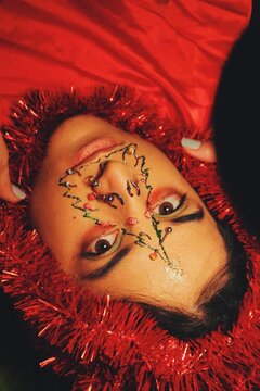closeup portrait of young woman with christmas tree decorations with piercing on face for 2022 new year celebration *3