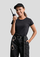 African-American female security guard with radio transmitter on light background