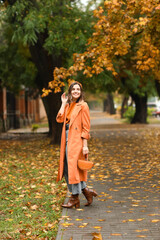 Happy young woman with stylish handbag on autumn city street