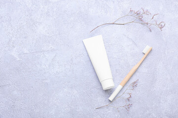 Bamboo tooth brush with paste and flowers on light background