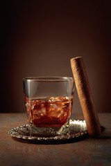 Whiskey with ice and cigar on a rusty background.