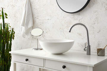Table with sink, mirror and toothbrush near light wall