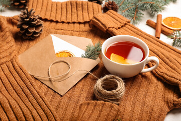 Sweater, envelope with card, rope and cup of tea on light background, closeup. Hello winter