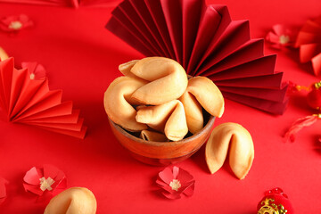 Bowl with tasty fortune cookies and Chinese symbols on color background