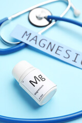 Bottle of pills, word MAGNESIUM and stethoscope on color background, closeup