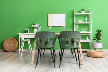 Interior of stylish dining room with tables, shelving unit and green wall