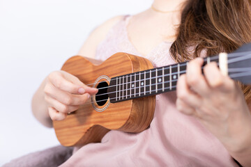 Fototapeta premium Hand of girl playing ukulele, small stringed instrument