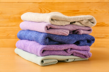 Obraz na płótnie Canvas Stack of different cozy sweaters on wooden background