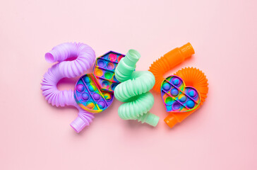 Colorful Pop Tubes and Pop it fidget toys on pink background