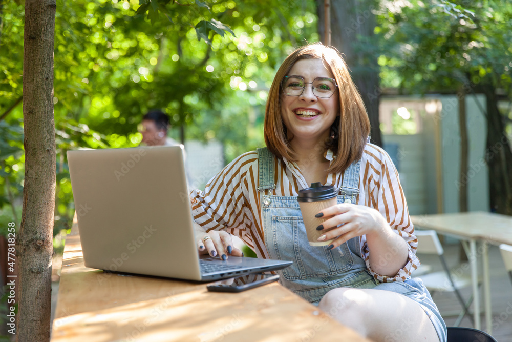 Wall mural Young pretty woman with laptop in outdoor coworking space