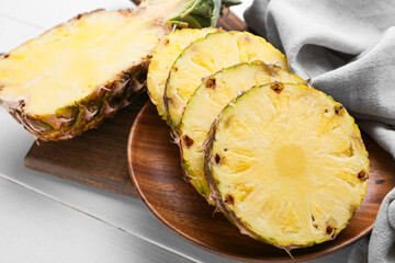 Plate with cut pineapple on light wooden background, closeup