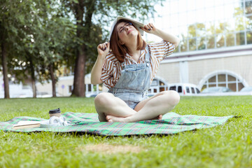 I don’t want to study! Young emotional woman student with textbook with homework above head in...