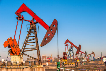 Oil pumps are running in the sunset at the oil field. On the Bohai coast of China