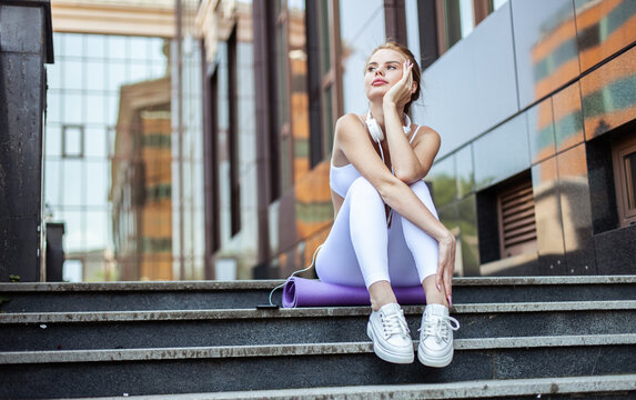 Beautiful fit woman sitting on stairs in urban environment