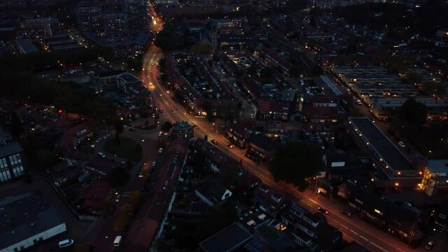 Aerial bird view of dark city shot after sundown showing cars driving over well lit roads and apartment buildings in neighbourhood night flight by stable drone equipment 4k high resolution footage
