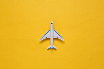 Toy passenger plane on yellow background. Voyage, Travel concept. Top view