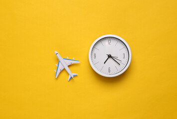 Time to travel. Passenger plane and clock on a yellow background. Top view