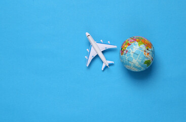 Toy passenger plane and globe on blue background. Voyage, Travel, summer vacation concept. Top view