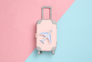 Toy passenger plane and luggage on blue pink background. Voyage, Travel, summer vacation concept. Top view