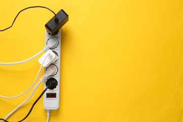 Electrical Extension cord with different plugs and adapters on yellow background. Top view. Copy...