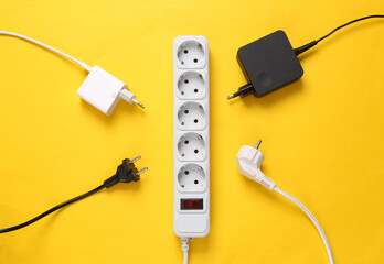 Electrical Extension cord with different plugs and adapters on yellow background. Top view. - obrazy, fototapety, plakaty